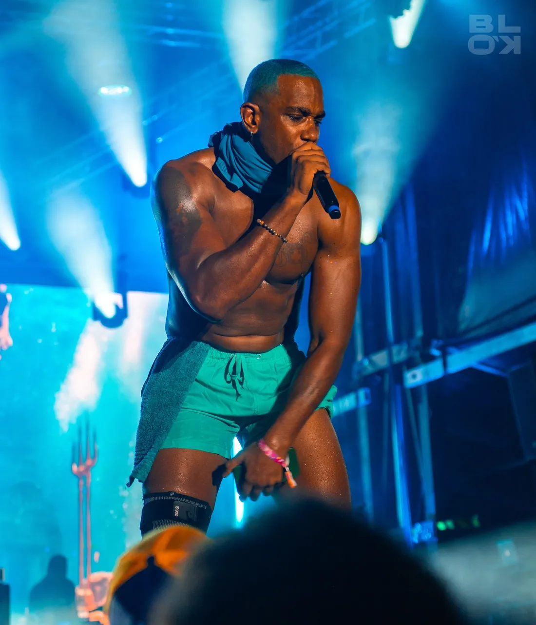 Artiste en tenue turquoise sous les projecteurs bleus